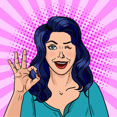 Wall Mural - Winking brunette pop art. The black-haired beauty shows with fingers that she is doing well. Vector illustration in comic style.