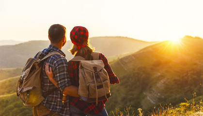 happy couple man and woman tourist at top of mountain at sunset   a hike in summer