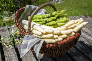 Fresh raw white and green asparagus as close-up in a basket outdoor at a wooden bridge