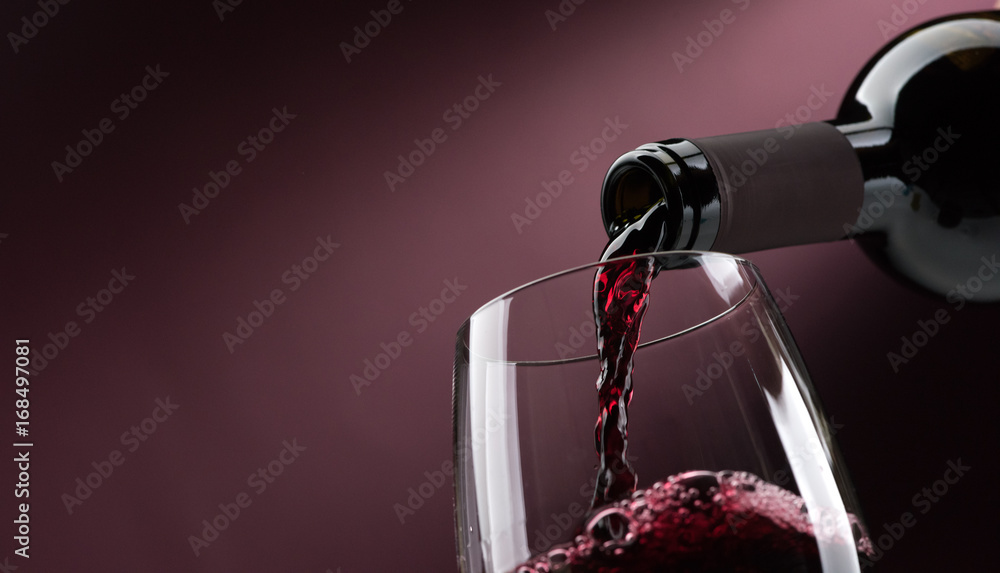 Pouring red wine into a wineglass - obrazy, fototapety, plakaty 