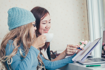 Businesswoman giving presentation to her partner about report of production plan in coffee time at coffee shop.