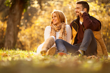 Love couple sitting under a tree in the colorful spring garden at sunset