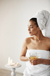 © Cookie Studio - African girl with towel on head holding glass smiling looking in side resting in spa resort.