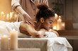 © Cookie Studio - Tender african girl smiling enjoying massage with closed eyes in spa resort.