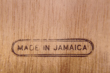 A Piece Of Wood With A Burnt Engraving On The Lower Side With The Words Made In Jamaica.
