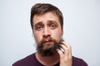 Confused and uncertain man scratching messy beard