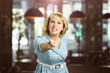Unhappy yelling woman, blurred background. Frustrated middle aged woman shouting and threatening with index finger to someone, blurred background.