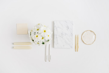 Wall Mural - Flat lay home office desk. Woman workspace with chamomile flowers bouquet and marble diary on white background. Top view feminine background.