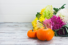 Pile Of Orange Pumpkins With Fall Flowers On White Wooden Table With Copy Space