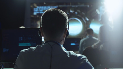 Movement shot back view of man working on space mission in control center. Elements of this image furnished by NASA.