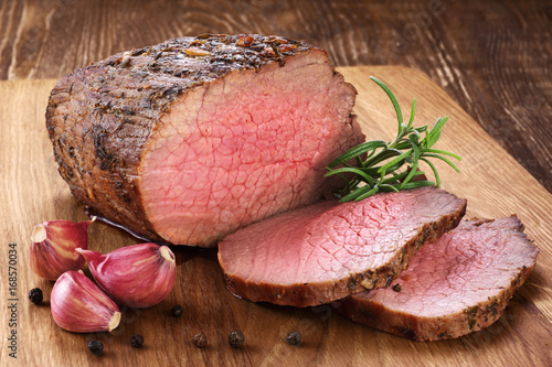 Cuadros en Lienzo Carne cocida al horno, ajo y romero en un fondo de madera