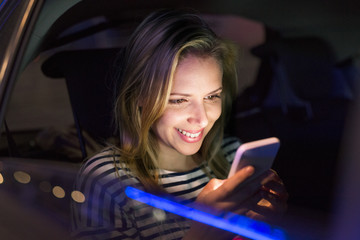 Woman with smartphone in her car at night.