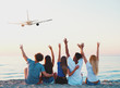 © alphaspirit - Group of friends having fun on the beach with flying aircraft