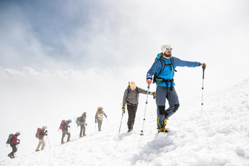 A group of mountaineers climbs to the top of a snow-capped mountain