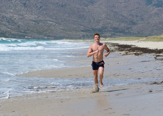 Wall Mural - young man jogging on the sea beach