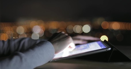 Woman typing on digital tablet at night