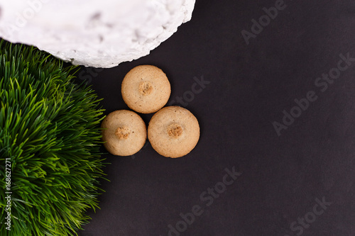 Fotografie, Obraz Wheat cookies with white snag and artificial green grass on black background