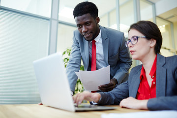 Female employer showing her subordinate new ideas and online data for project