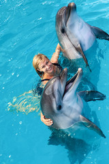 Wall Mural - Coach swims in the water with dolphins. Dolphin Assisted Therapy.