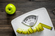 © 9dreamstudio - Lose weight concept. Bathroom scale, measuring tape, apples on wooden background top view