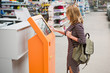 © scharfsinn86 - A woman chooses the goods online at the self-service device in hardware store