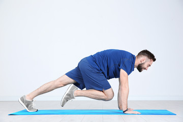 Sticker - Sporty young man training legs on mat in gym