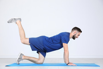 Sticker - Sporty young man training legs on mat in gym