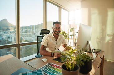 Wall Mural - Smiling male designer sitting at his desk