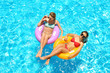 © Africa Studio - Beautiful young girls relaxing on inflatable rings in blue swimming pool