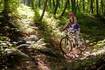 young girl in sport wear with bicycle riding in forest in summer