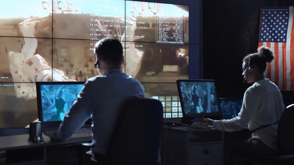 Back view of people working and managing flight in mission control center. Elements of this image furnished by NASA.