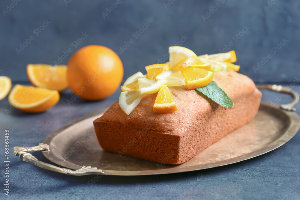 Tray with delicious citrus cake and sliced fruits on table