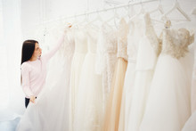 Woman Choosing Wedding Dress In Shop. Concept Engagement, Preparation For The Main Day Of The Girl.