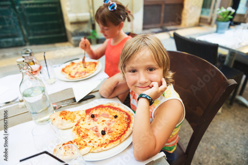 Zdjęcie XXL Szczęśliwa chłopiec łasowania dzieciaka pizza w restauraci. Menu dla dzieci, włoska pizza w kształcie zwierząt dla najmłodszych