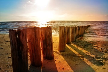  Holzbuhnen an der Nordsee beim  orangenen Sonnenuntergang 