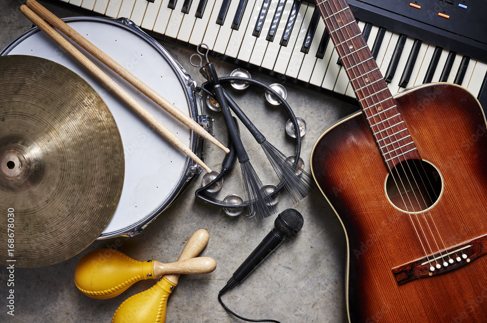 a group of musical instruments including a guitar, drum, keyboard, tambourine. - obrazy, fototapety, plakaty 