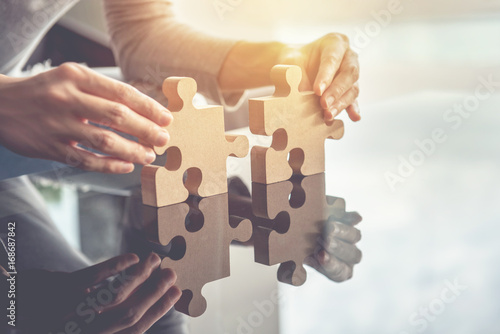 Fotografia Closeup hand of woman connecting jigsaw puzzle with sunlight effect, Business so