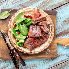 Sticker - Beef steak with spinach, pomegranate in plate on wooden board