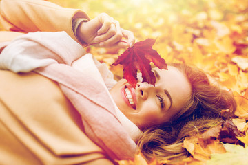 Wall Mural - beautiful happy woman lying on autumn leaves