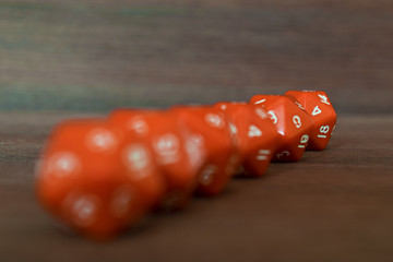 Wall Mural - Line of many red dices on wooden board. Twenty sides with white numbers. Artistic blurring.