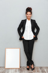 Poster - Young african business woman over grey wall looking camera