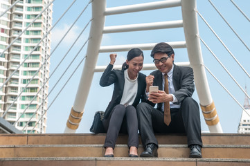 Wall Mural - Asian middle business man and woman looking to smart phone feel happy and success with their works.