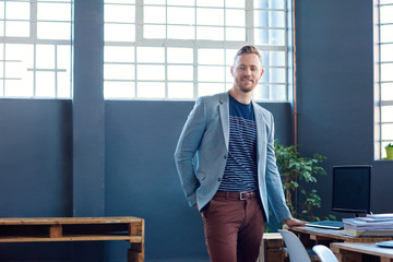 Confident young entrepreneur standing alone in a modern office