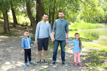 Wall Mural - Smiling gay couple with children in park