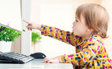 Wall Mural - Toddler girl pointing to her computer screen