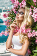 Portrait beautiful phenomenal stunning elegant sexy blonde model woman with perfect face wearing a glasses stands with elegant outfit on amazing view with flowers and yachts in Cannes, France