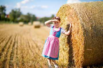 Wall Mural - Cute little kid girl in traditional Bavarian costume in wheat field