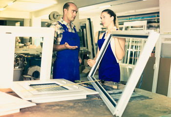 Foreman explaining plastic windows assembly process to young female worker