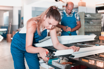 Female worker cutting metal-plastic profiles in workshop, using nippers