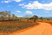 Red Dirt Road Go To The Mountain With Forest And Blue Clouds Sky At Phuhinrongkla National Park, Phitsanulok, Thailand